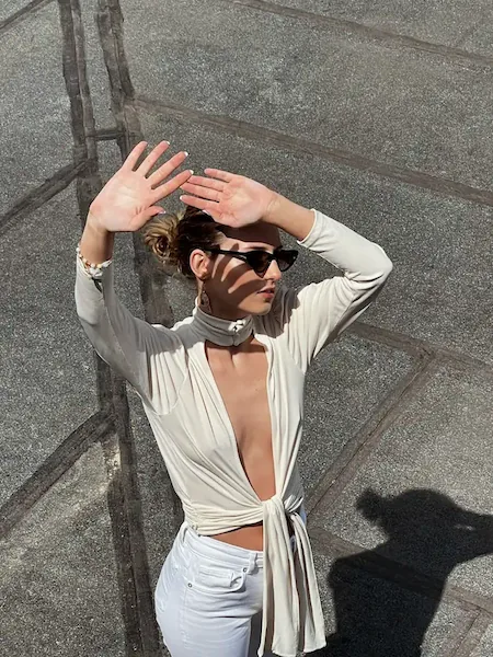 Fashion UGC creator posing in a stylish white top and sunglasses, showcasing high-end aesthetic apparel content.